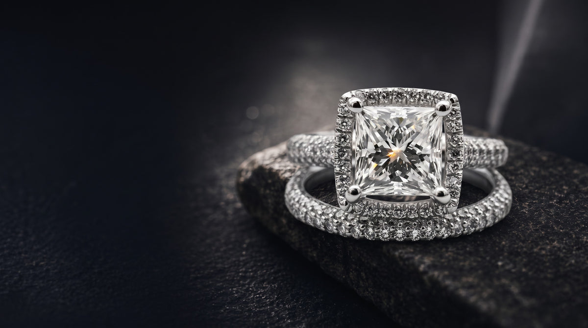 Pear-cut lab-grown diamond engagement ring with a pavÃ© halo, photographed on dark stone