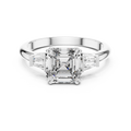 Diamond ring with a central emerald-cut diamond and baguette side stones on a white background