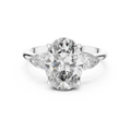 A front close-up view of a luxury three-stone lab-grown diamond engagement ring in solid white gold, highlighting a brilliant 2.75 carat oval center diamond and two pear-shaped side stones.