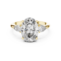 A front close-up view of a luxury three-stone lab-grown diamond engagement ring in solid yellow gold, highlighting a brilliant 2.75 carat oval center diamond and two pear-shaped side stones.