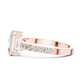 A side view of a luxury Toi et Moi lab-grown diamond engagement ring crafted in solid rose gold, showcasing the emerald-cut center diamond and brilliant pavé diamonds along the band.