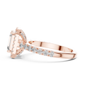 Low angle side view of rose gold emerald cut engagement ring showing halo and pave band