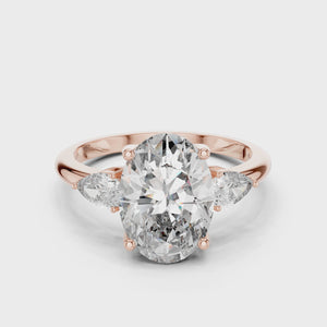 A stunning three-stone lab-grown diamond engagement ring in 14k rose gold, featuring a massive 2.75 carat oval-cut center diamond flanked by two brilliant pear-cut side stones on a clean white background.