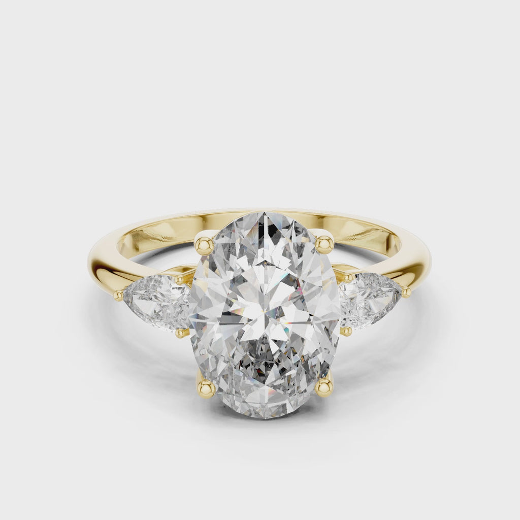 A video showcasing a luxury three-stone lab-grown diamond engagement ring in solid yellow gold, highlighting a brilliant 2.75 carat oval center diamond paired with two pear-cut side stones.