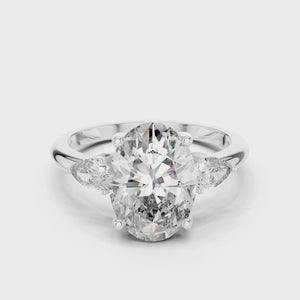 A video showcasing a luxury three-stone lab-grown diamond engagement ring in solid white gold, highlighting a brilliant 2.75 carat oval center diamond paired with two pear-cut side stones.