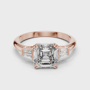 Luxury three-stone diamond ring video in rose gold, highlighting the brilliant clarity of a 1.80ct emerald-cut center stone and 0.14ct baguette-cut side accents.
