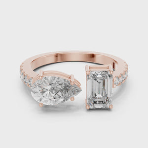 A video showcasing a luxury Toi et Moi lab-grown diamond engagement ring crafted in solid rose gold, highlighting a 0.86 carat emerald-cut diamond and a 1.00 carat pear-shaped diamond on a pavé accented open band.