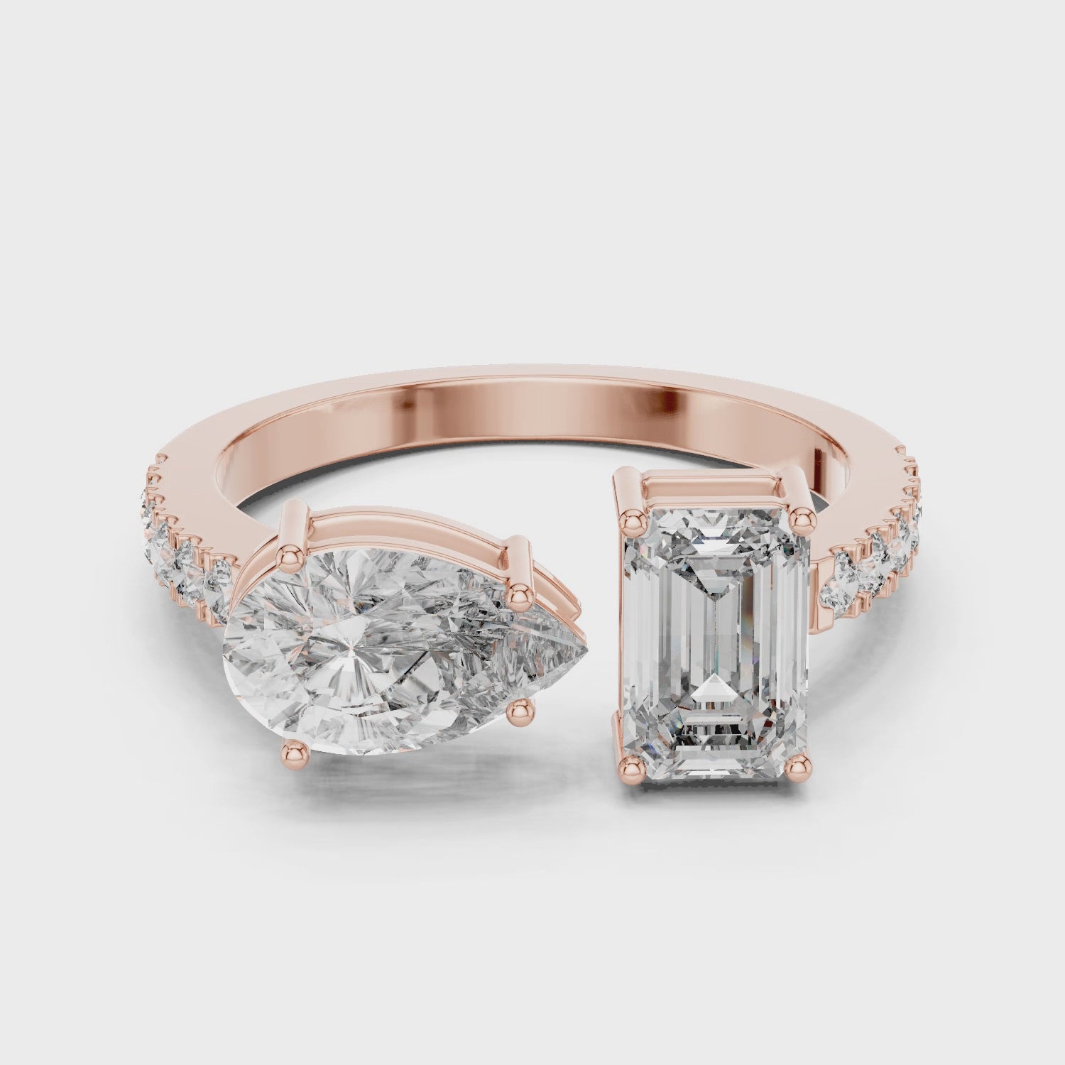 A video showcasing a luxury Toi et Moi lab-grown diamond engagement ring crafted in solid rose gold, highlighting a 0.86 carat emerald-cut diamond and a 1.00 carat pear-shaped diamond on a pavé accented open band.